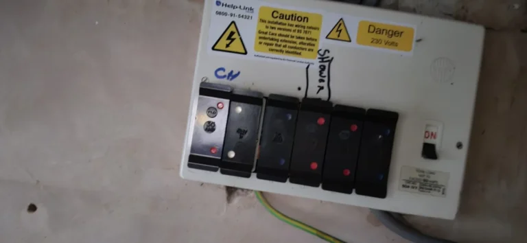 An older fuse board with pull out fuse carriers and warning labels