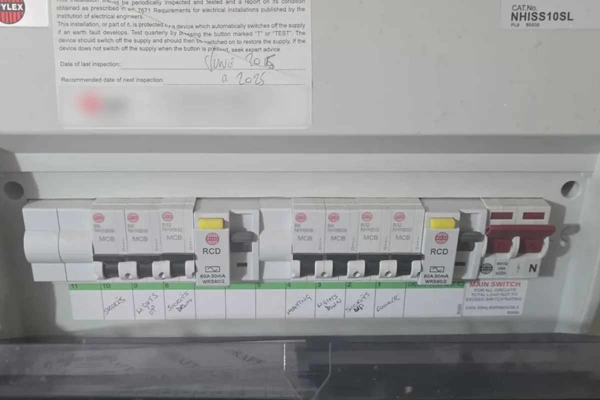 Consumer unit with two RCDs, each with a yellow test button, a row of circuit breakers and handwritten circuit labels